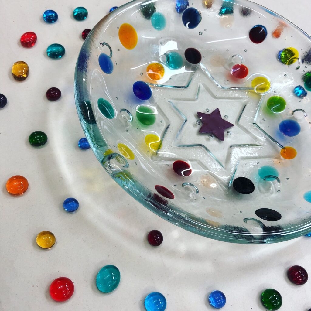 A fused glass "Smartie" bowl, with coloured glass dots, and a star impression on the underside, made at Rainbow Glass Studios on our beginners day class