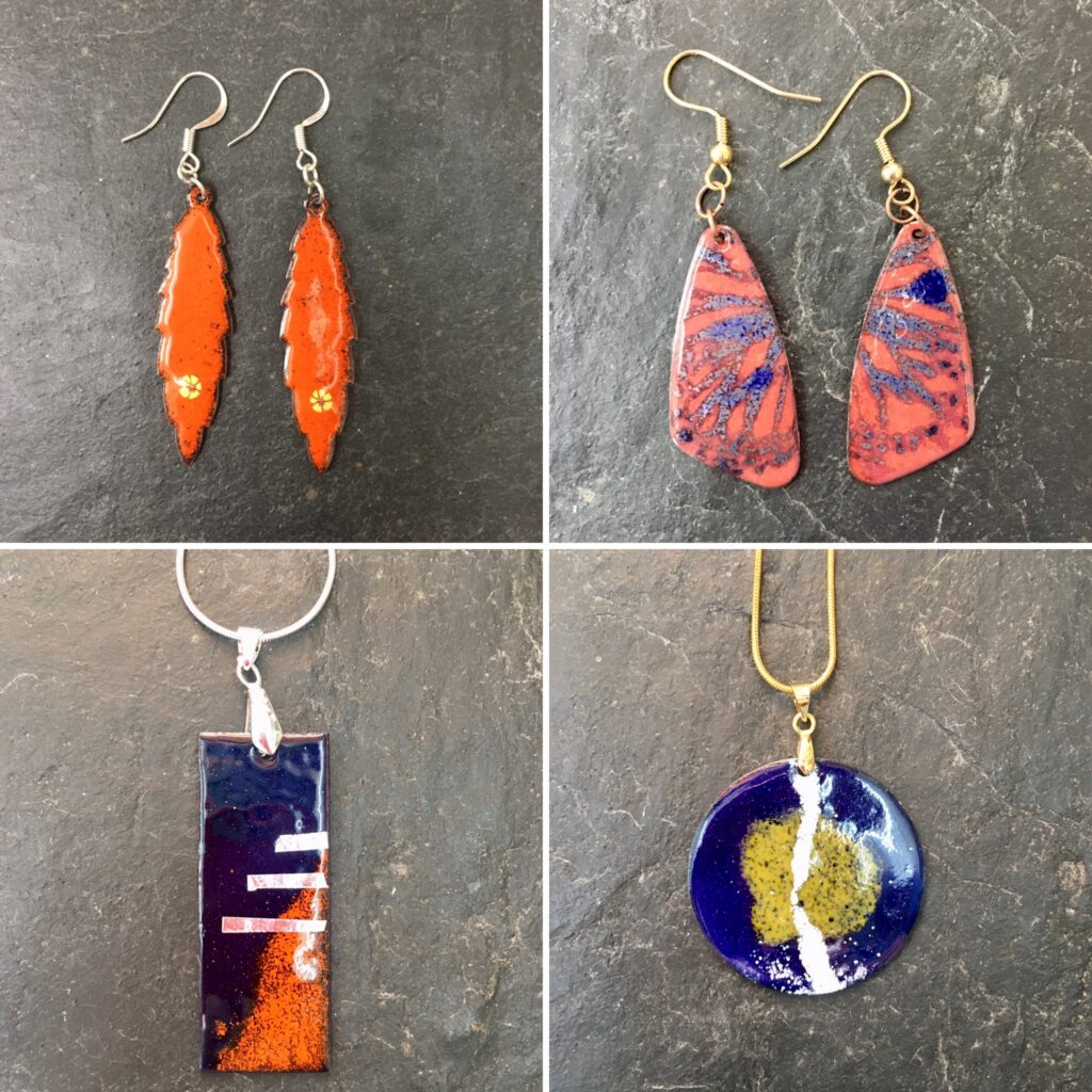 A collection of enamelled jewellery in blues and oranges, made by beginners on the Enamelling on Copper for Jewellery Day Course at Rainbow Glass Studios