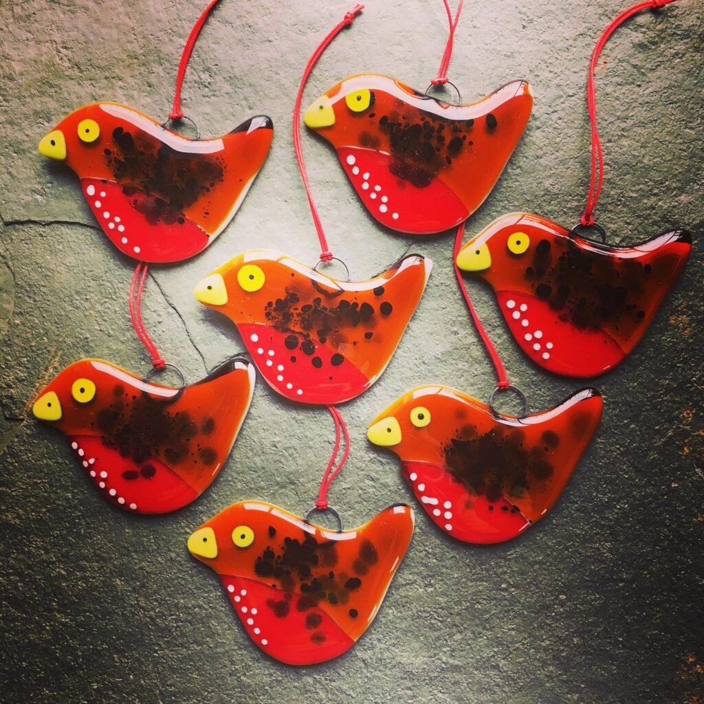 A chorus of Fused Glass Robin Christmas Tree Decorations made at Rainbow Glass Studios to a design by Eleanor Watson