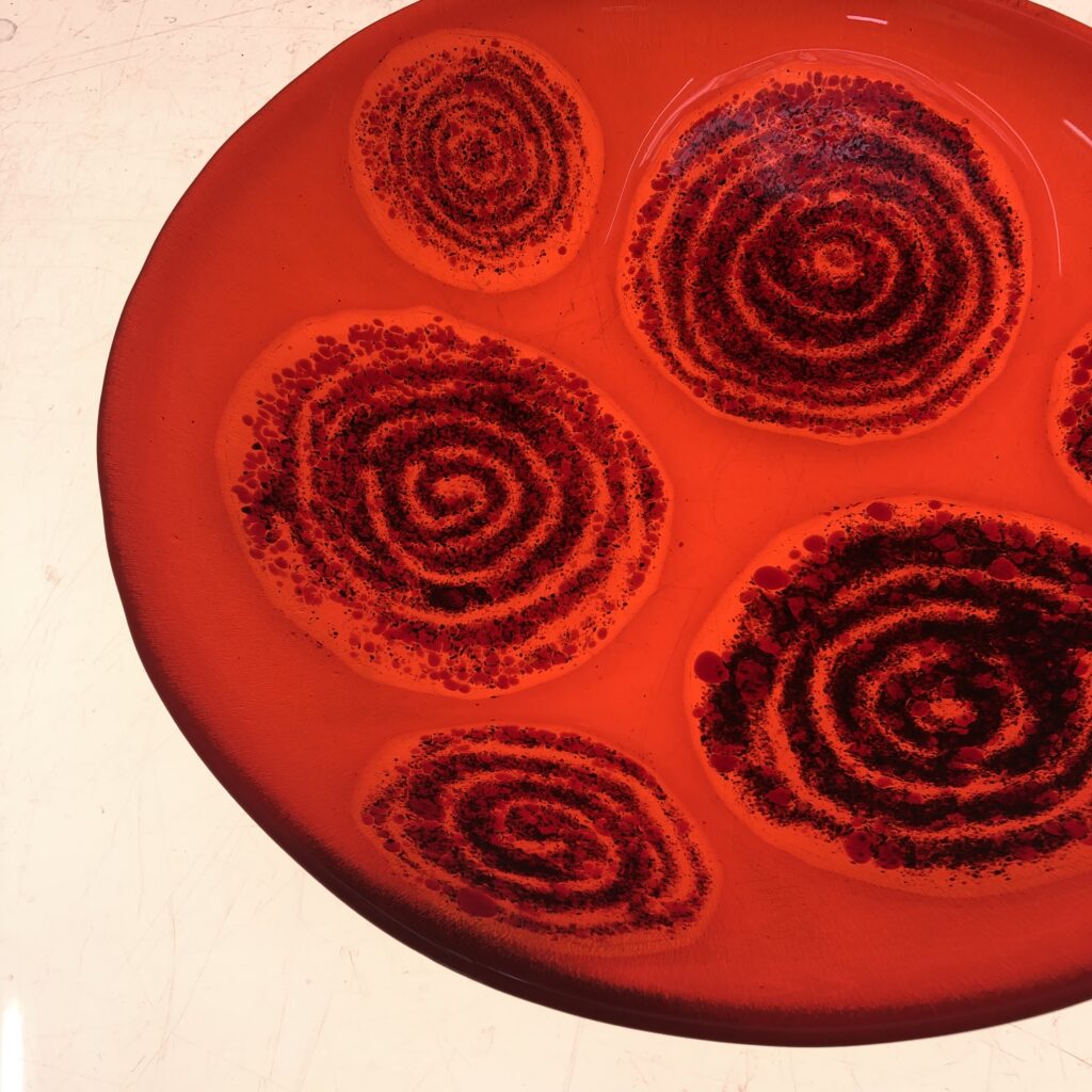 An orange fused glass bowl with swirl decoration - a beauty made by a first time student at Rainbow Glass Studios on the day course for beginners