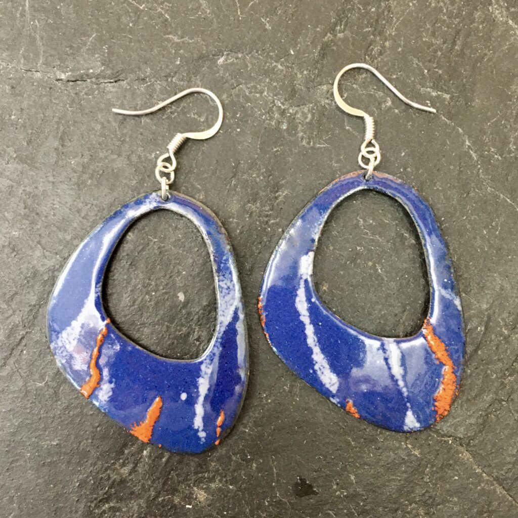 A pair of retro blue, white and orange hoop earrings, enamelled at Rainbow Glass Studios by a student on the beginners day course