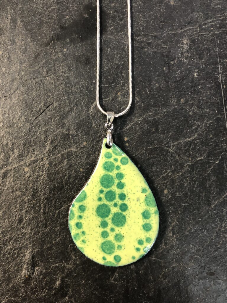 A pear drop shaped enamelled pendant in acid yellow and leaf green, beautifully enamelled by a complete beginner on our day Cours at Rainbow Glass Studios