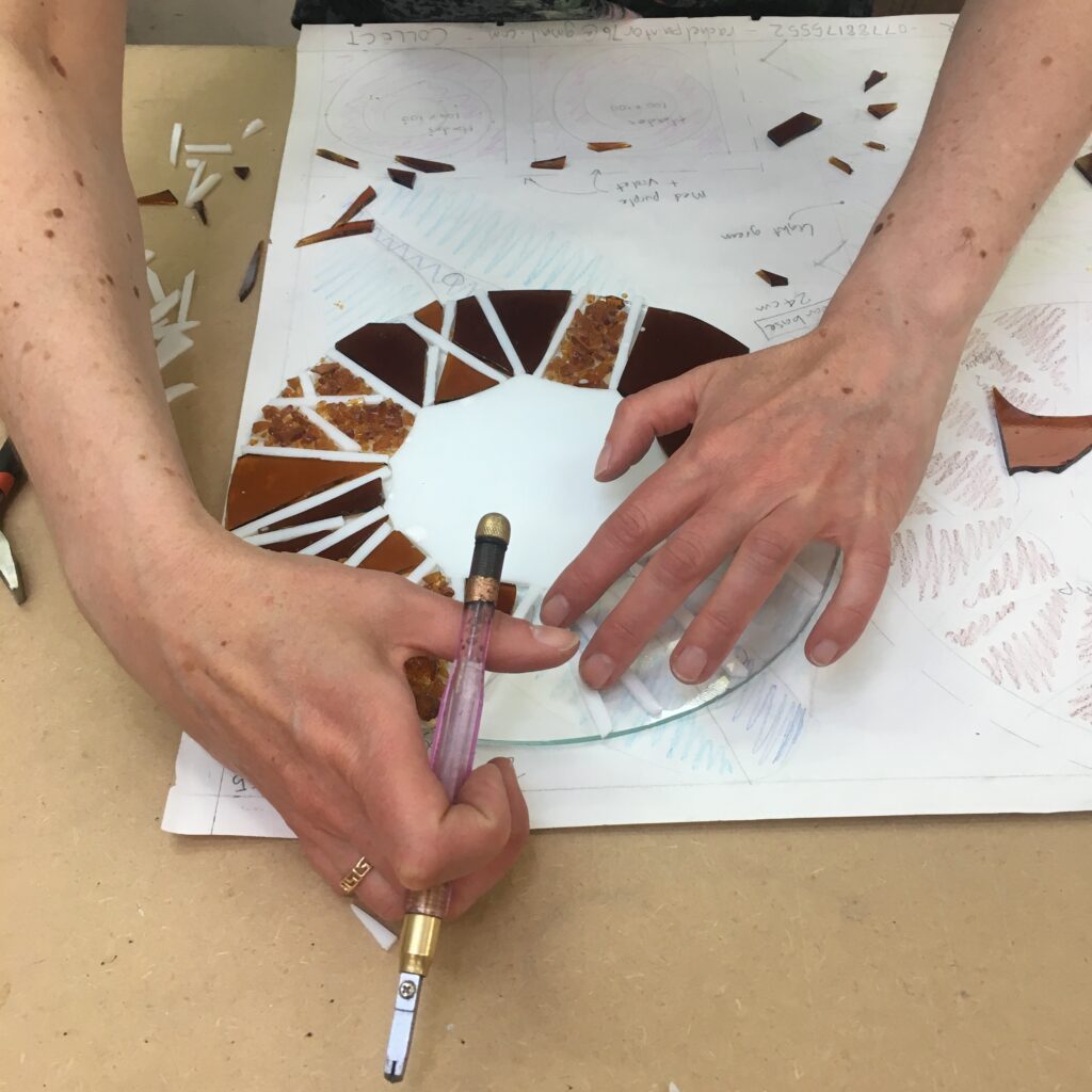 A student on the Fused Glass Beginner's day class assembling her floral slump before the first firing at Rainbow Glass Studios